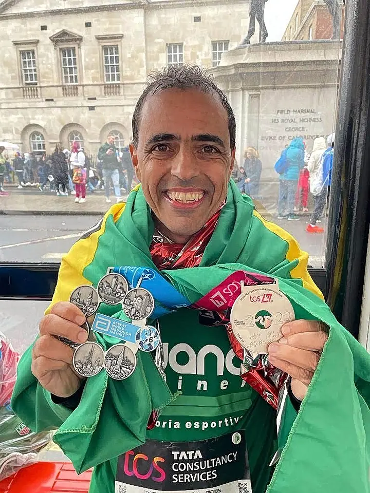 Aluno com a bandeira do Brasil e medalhas depois de uma maratona