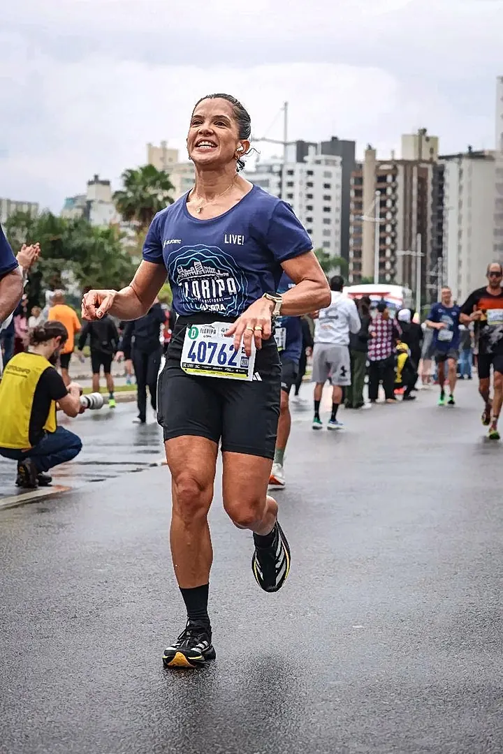 Aluna correndo sob chuva em uma maratona