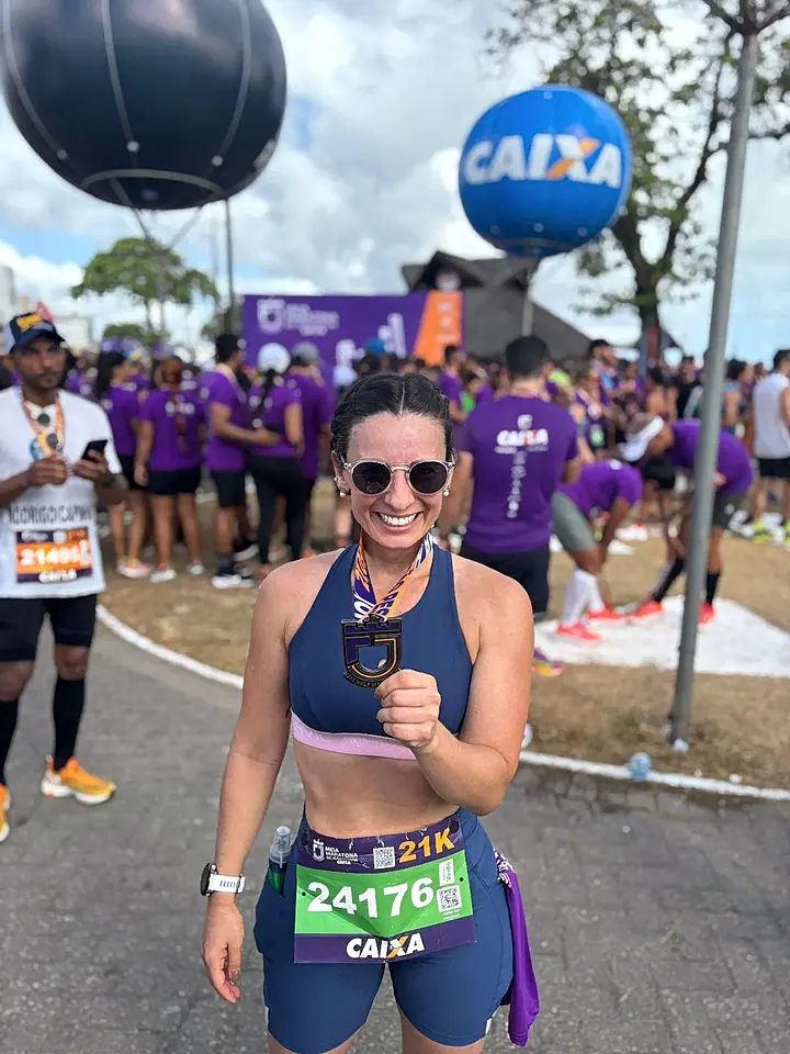 Aluna mostrando a medalha de uma meia maratona