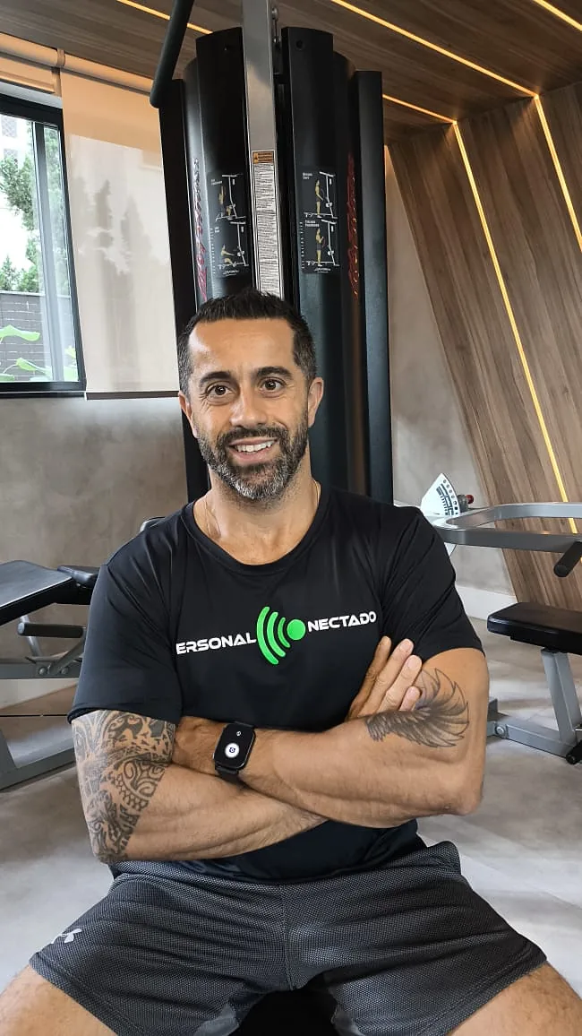 Gustavo Rodrigues Pereira sentado em um banco de musculação, de braços cruzados